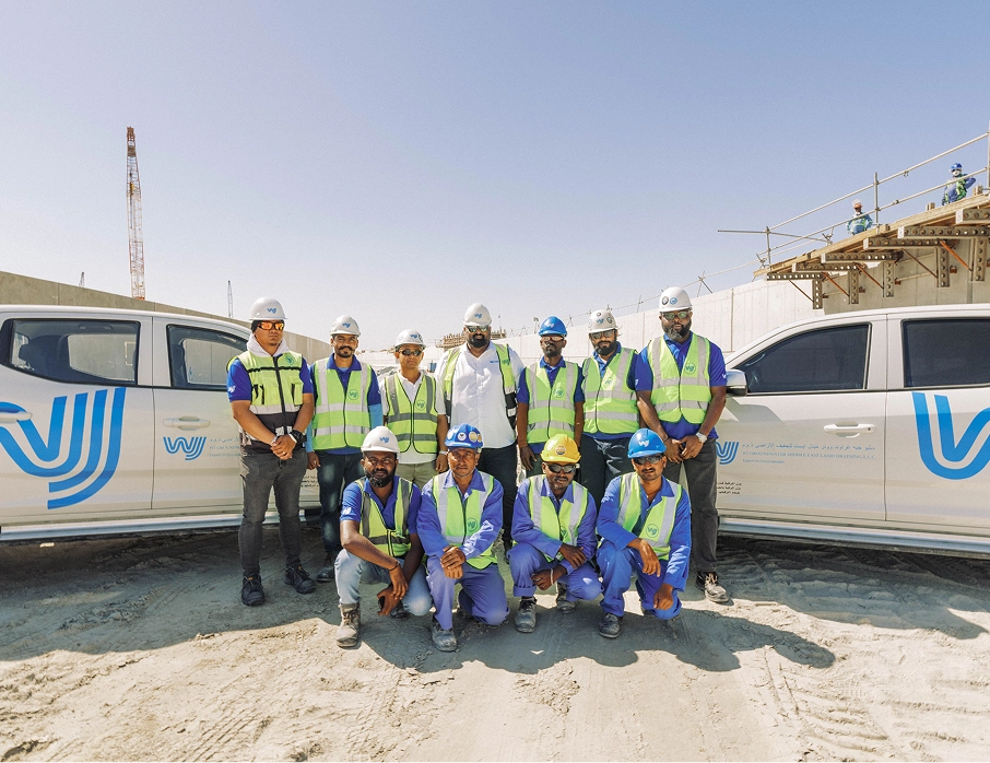 Groundwater control team at WJ Middle East building site, showcasing engineers and workers in safety gear standing in front of company vehicles, emphasizing project development and construction expertise.