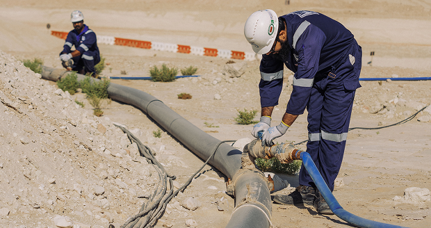 Preventive maintenance workers inspecting underground pipeline infrastructure at a construction site.